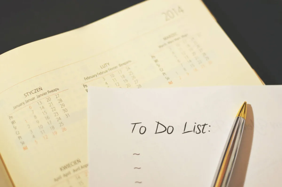 To do list on a sheet of paper over an open calendar