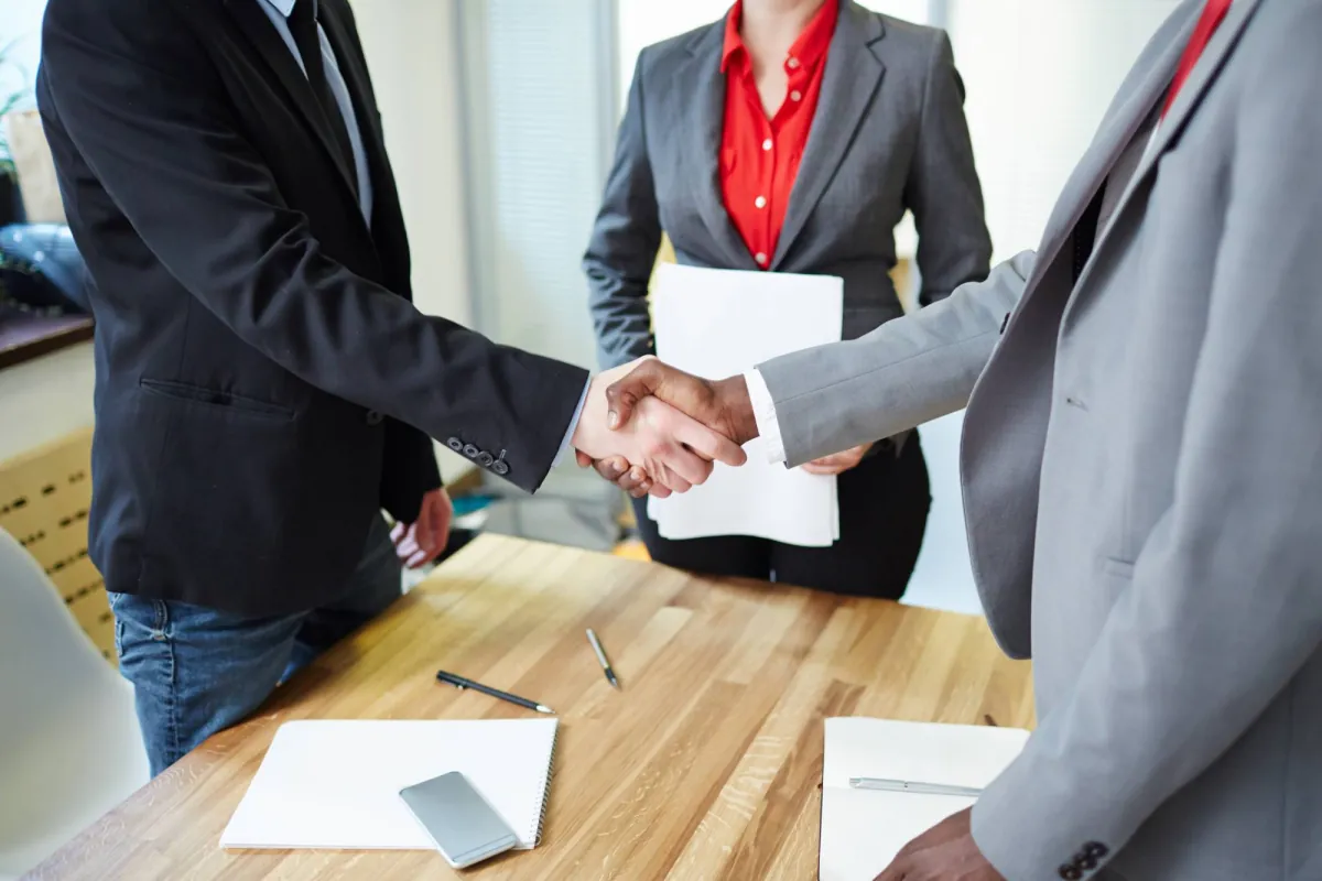 Business people shaking hands across a meeting table