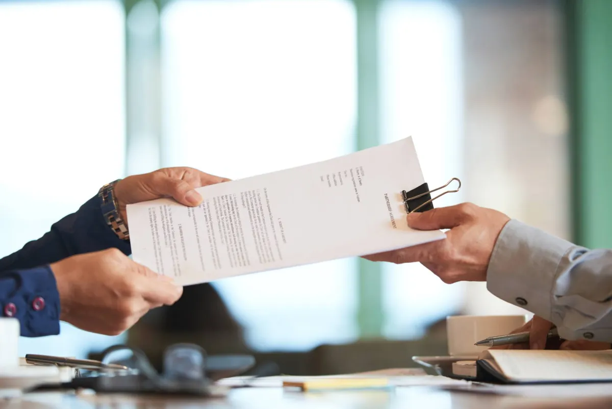 Two people handing over a printed document